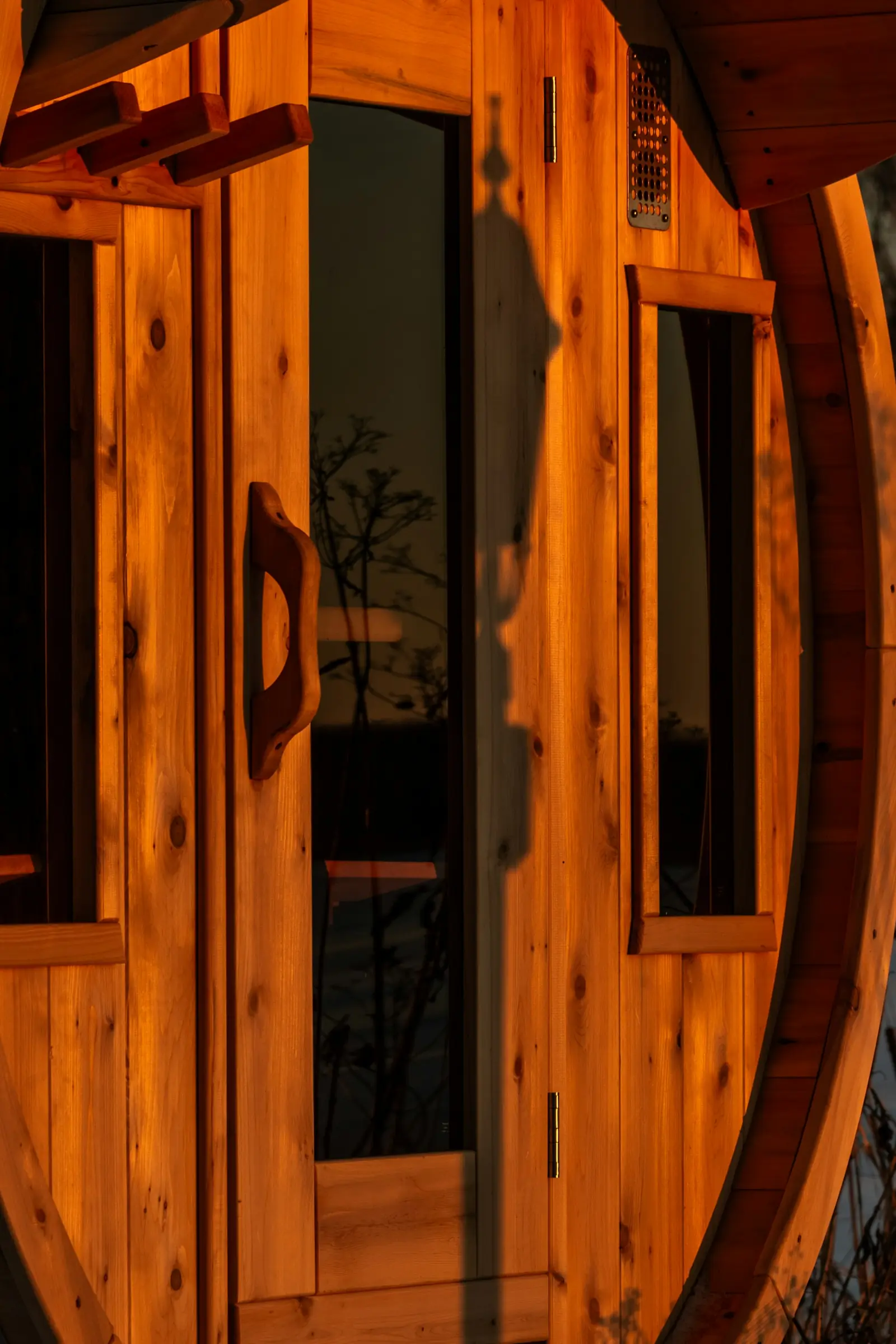 A glass door in the curved wooden end of a sauna