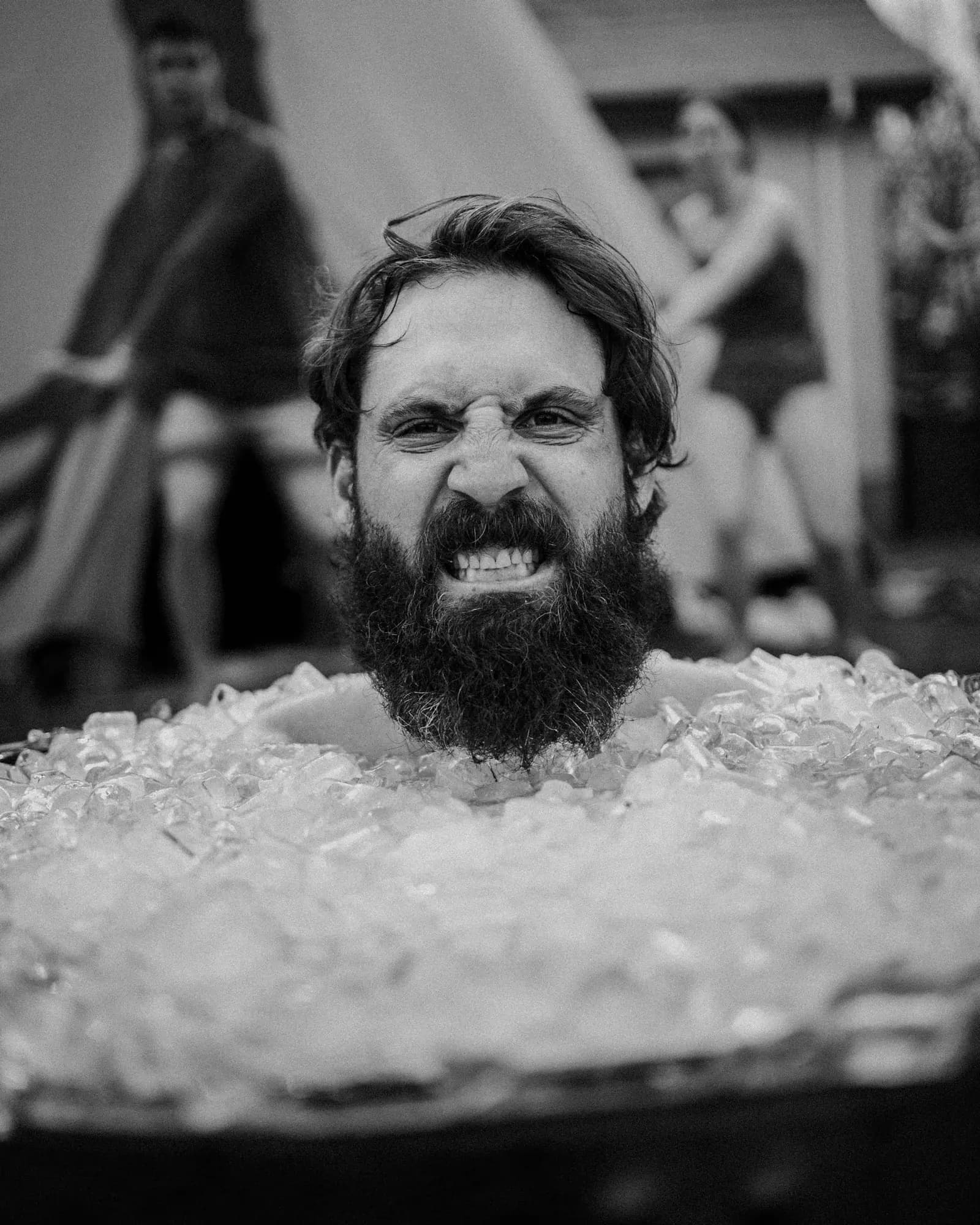 A man grimacing while sitting in a tub of ice (black-and-white photo)